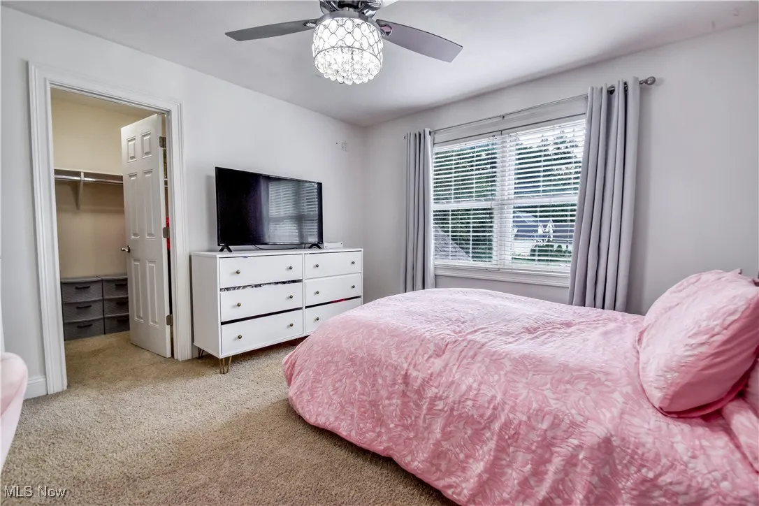 Bedroom featuring a walk in closet, carpet flooring, and ceiling fan