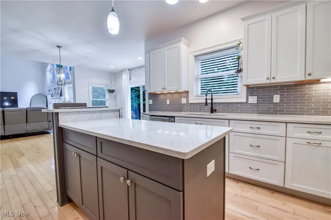 Kitchen with a kitchen island, decorative backsplash, light wood finished floors, white cabinets, and recessed lighting