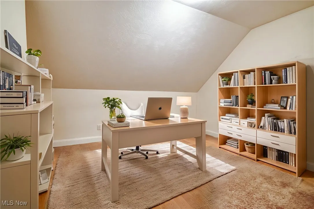 Office area with vaulted ceiling and light wood finished floors - virtually staged