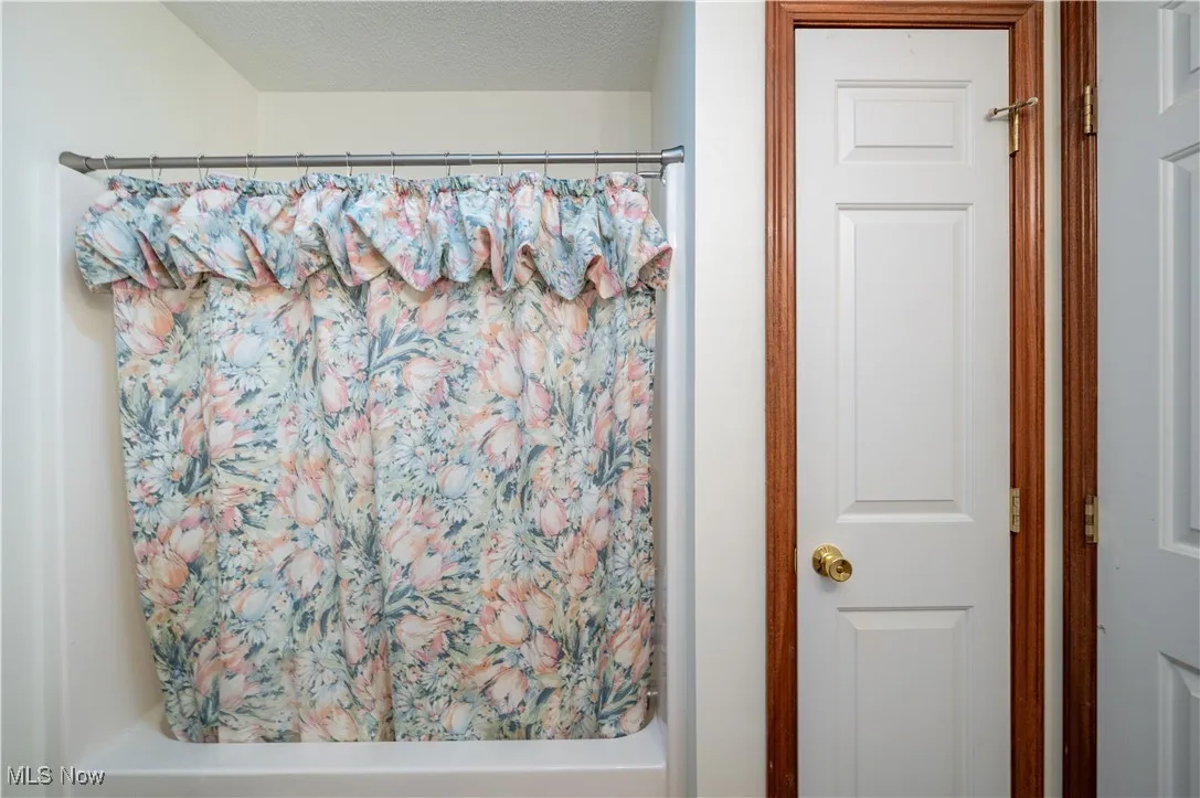 Bathroom with shower / tub combo with curtain and a textured ceiling