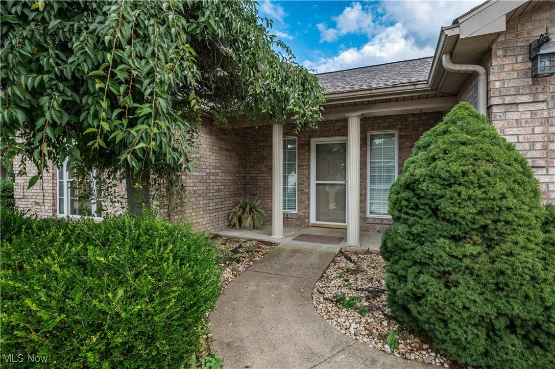 Entrance to property with a porch, brick siding, and a shingled roof