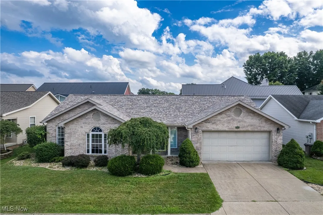 Ranch-style home featuring brick siding, a garage, driveway, and a front lawn