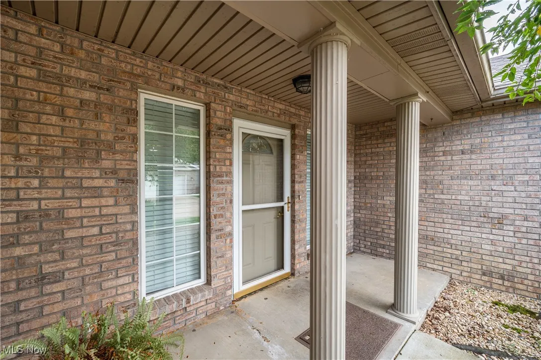 Entrance to property featuring brick siding and covered porch