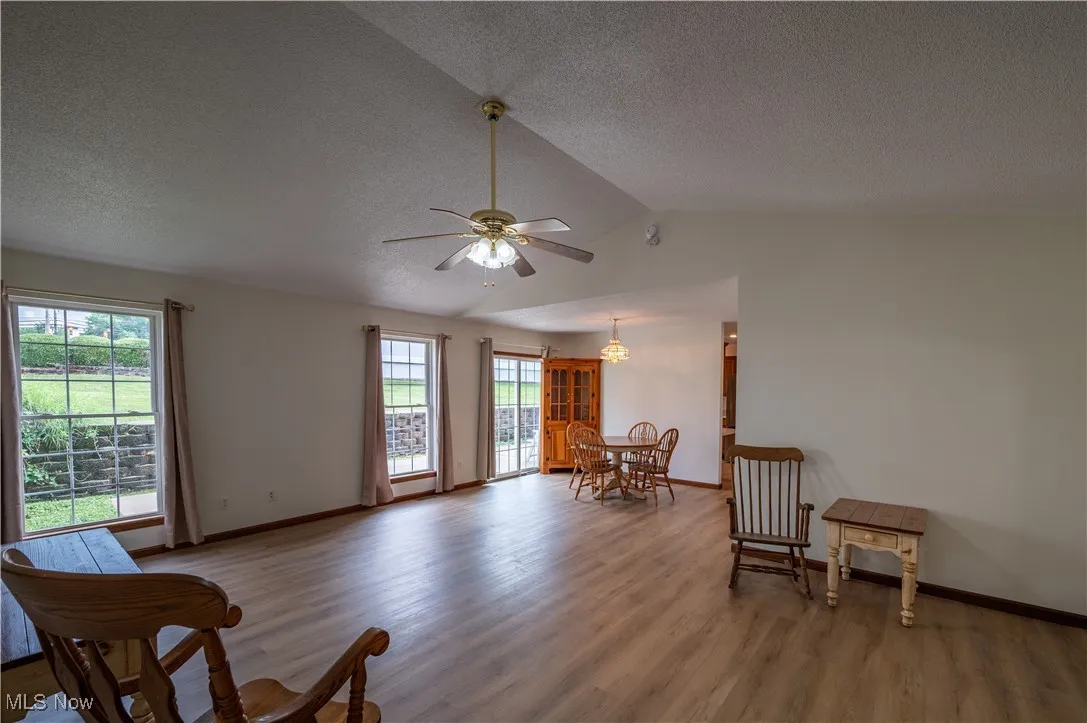Sitting room with wood finished floors, ceiling fan, a textured ceiling, and lofted ceiling