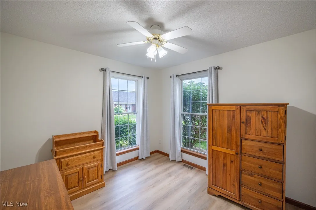 Bedroom featuring light wood finished floors, a ceiling fan, and a textured ceiling