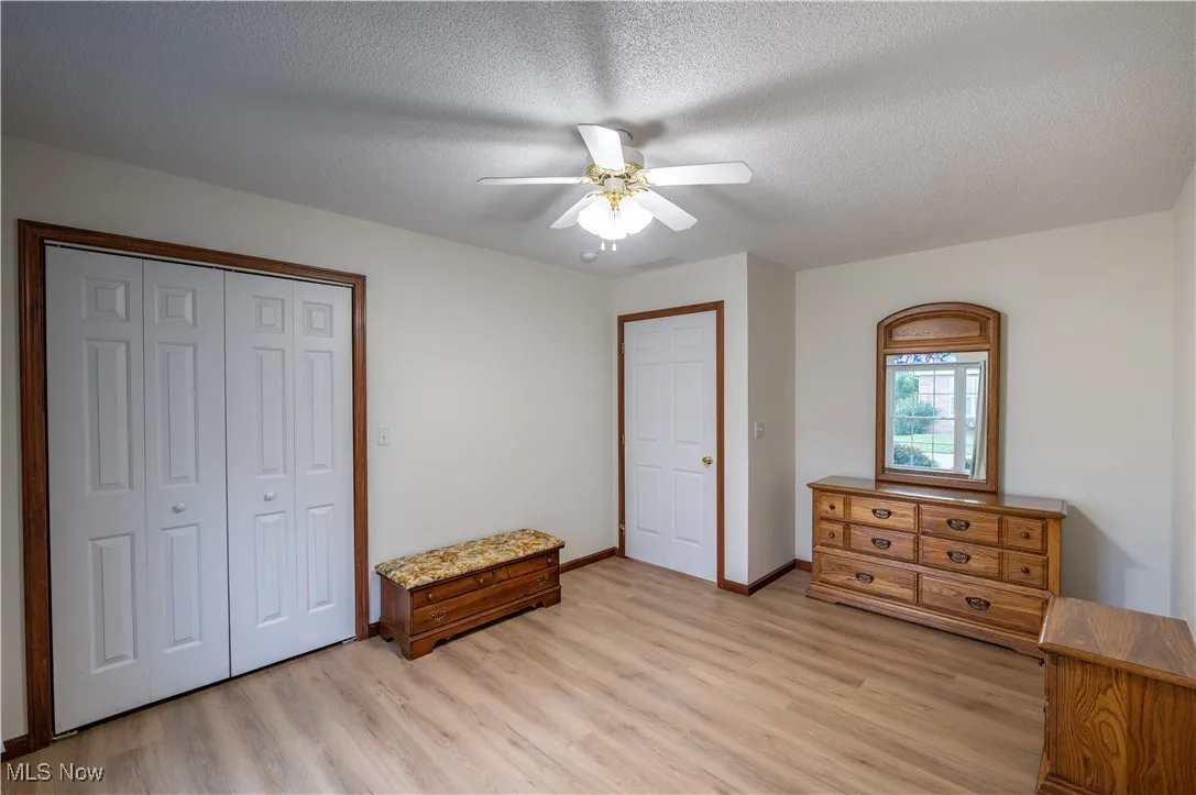 Bedroom featuring light wood finished floors, a closet, a ceiling fan, and a textured ceiling