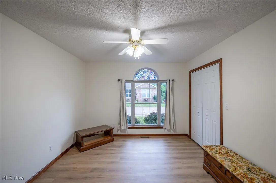 Empty room featuring light wood-type flooring, a ceiling fan, and a textured ceiling