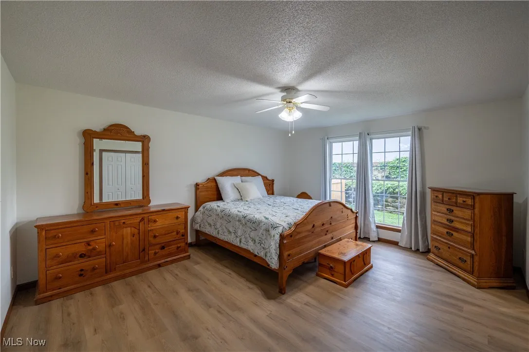 Bedroom with light wood-style flooring, a textured ceiling, and ceiling fan