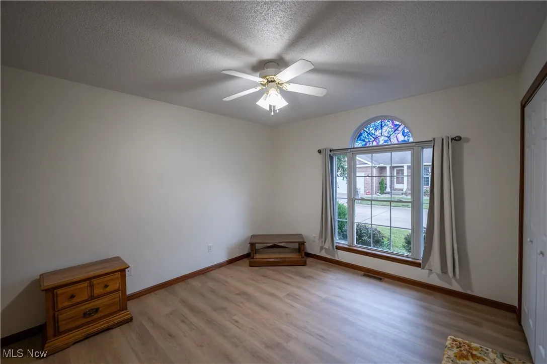Spare room featuring light wood finished floors, ceiling fan, and a textured ceiling