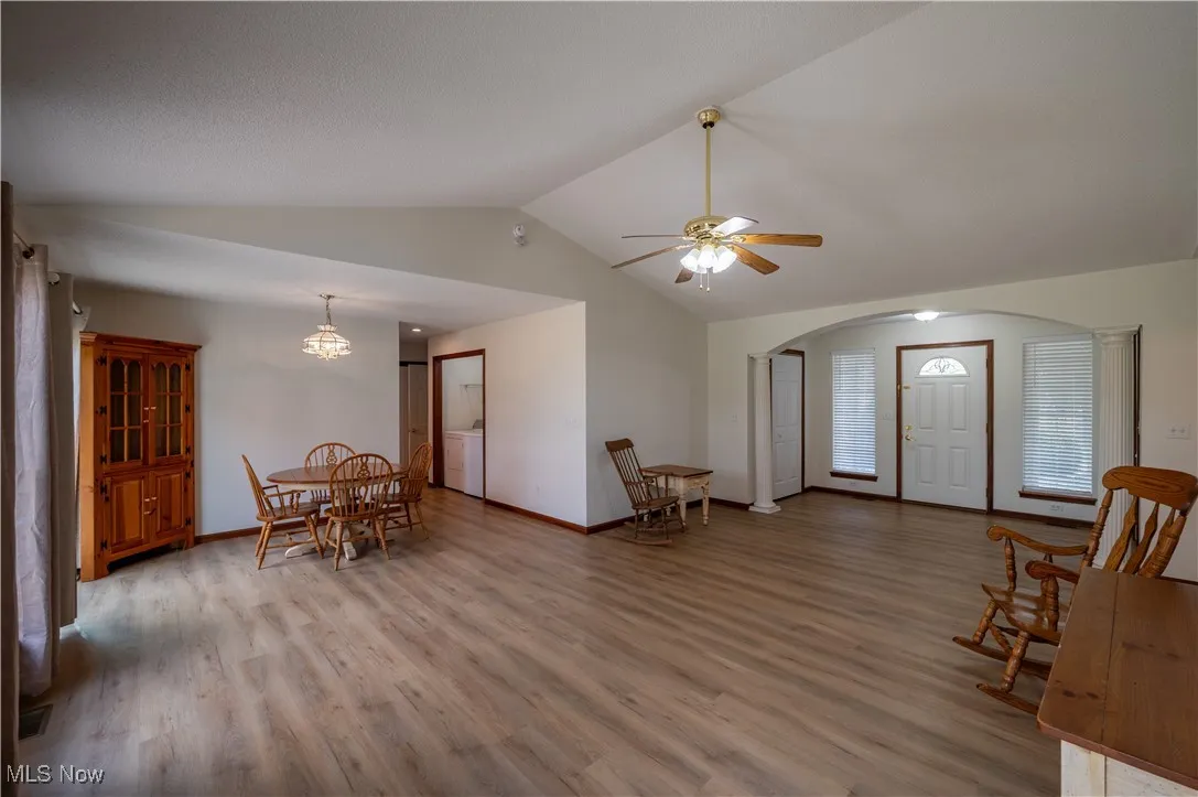 Entrance foyer featuring arched walkways, lofted ceiling, light wood-style floors, ceiling fan, and a chandelier