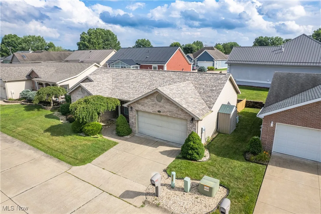 View of front of house featuring concrete driveway, a residential view, a front yard, and brick siding
