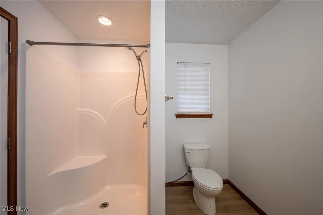 Bathroom featuring a shower stall, wood finished floors, and a textured ceiling