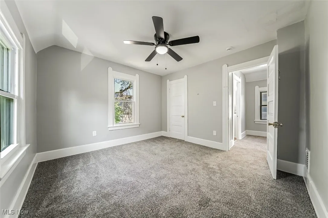 Unfurnished bedroom featuring carpet flooring, ceiling fan, and vaulted ceiling