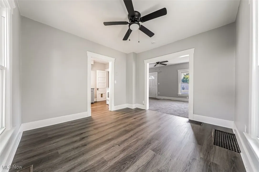 Spare room with dark wood-type flooring and a ceiling fan