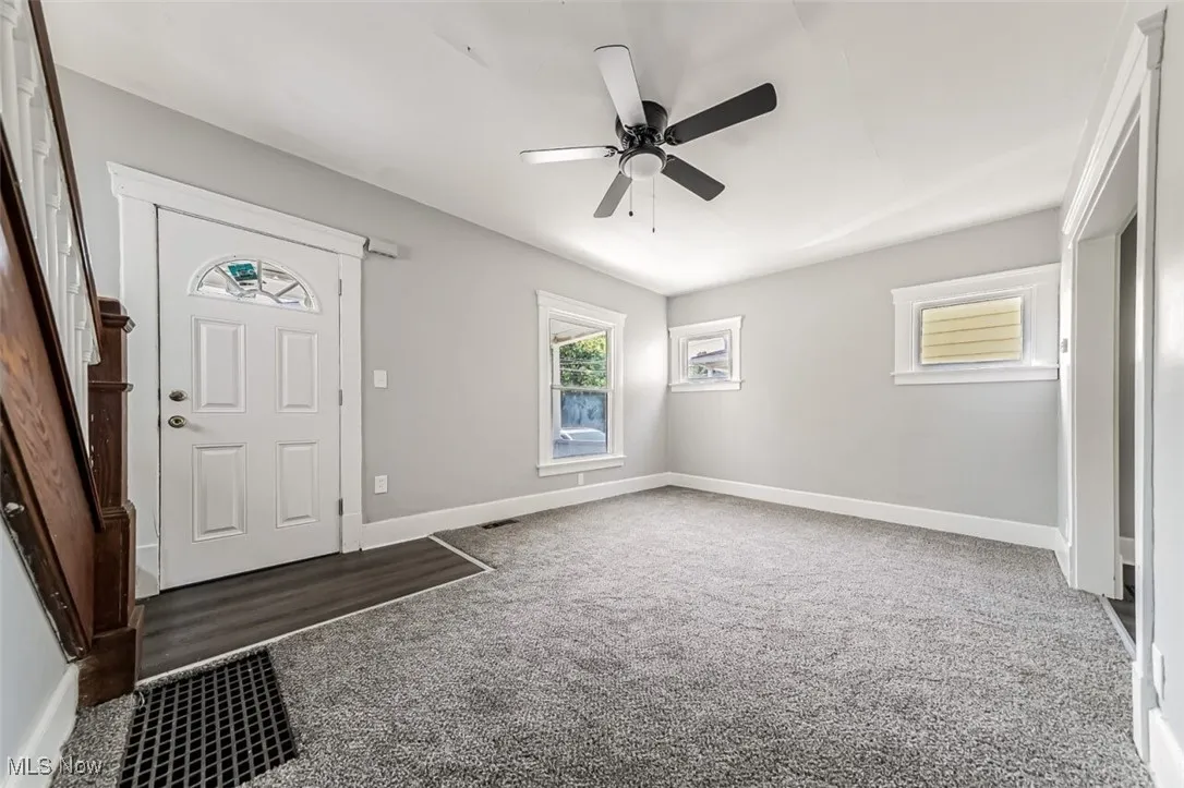 Foyer entrance with light carpet and a ceiling fan