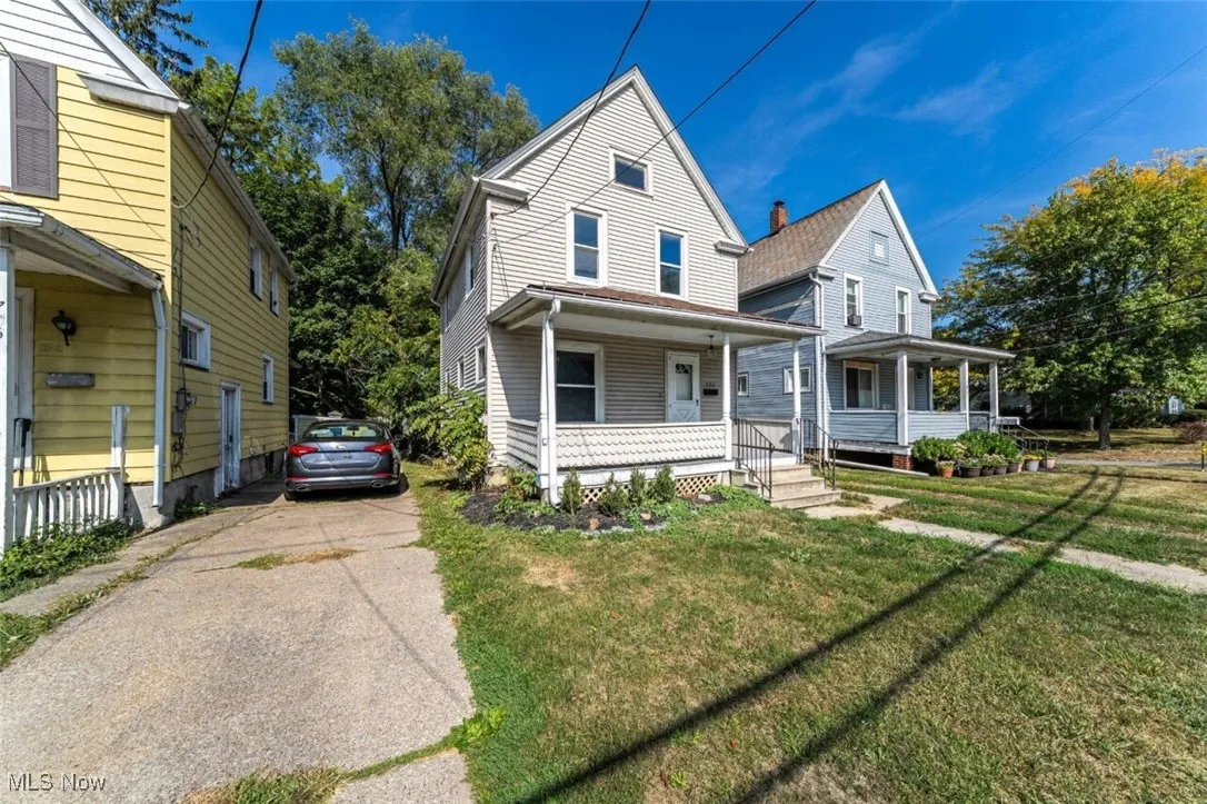 View of front of property featuring covered porch, concrete driveway, and a front yard