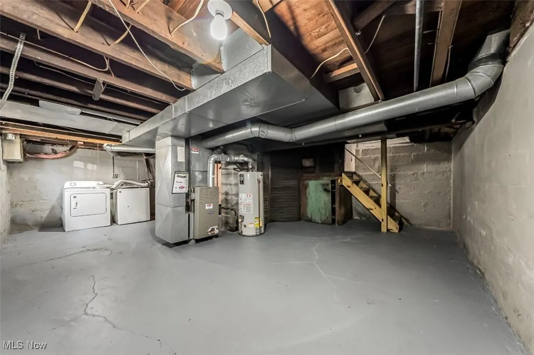 Unfinished basement with heating unit, stairs, gas water heater, and washer and dryer