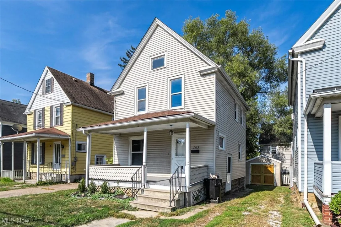 American foursquare style home featuring covered porch, a storage unit, and a front yard