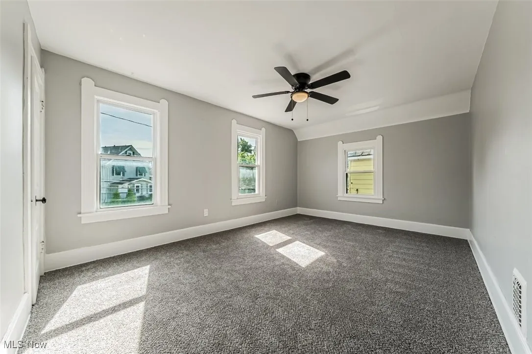 Spare room featuring carpet, plenty of natural light, and ceiling fan