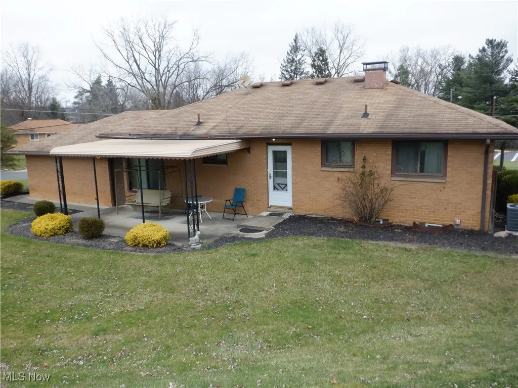 Rear view of property featuring cooling unit, a patio area, and back yard.