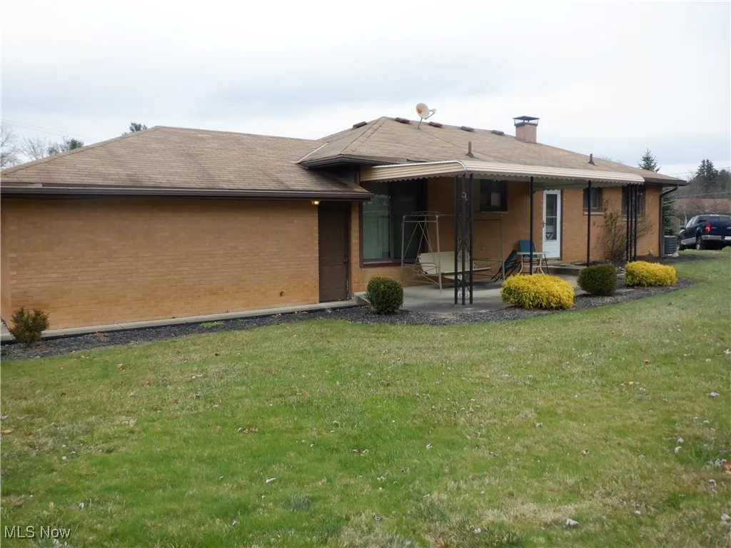 Back of house with a patio and a lawn and landscaping.