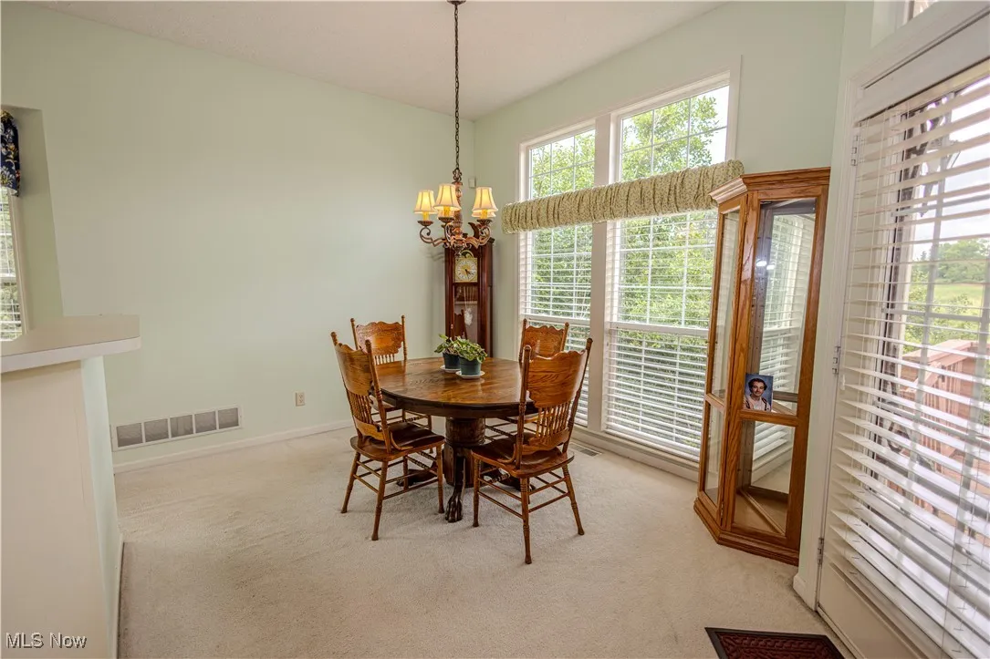Dining space with light colored carpet and a chandelier