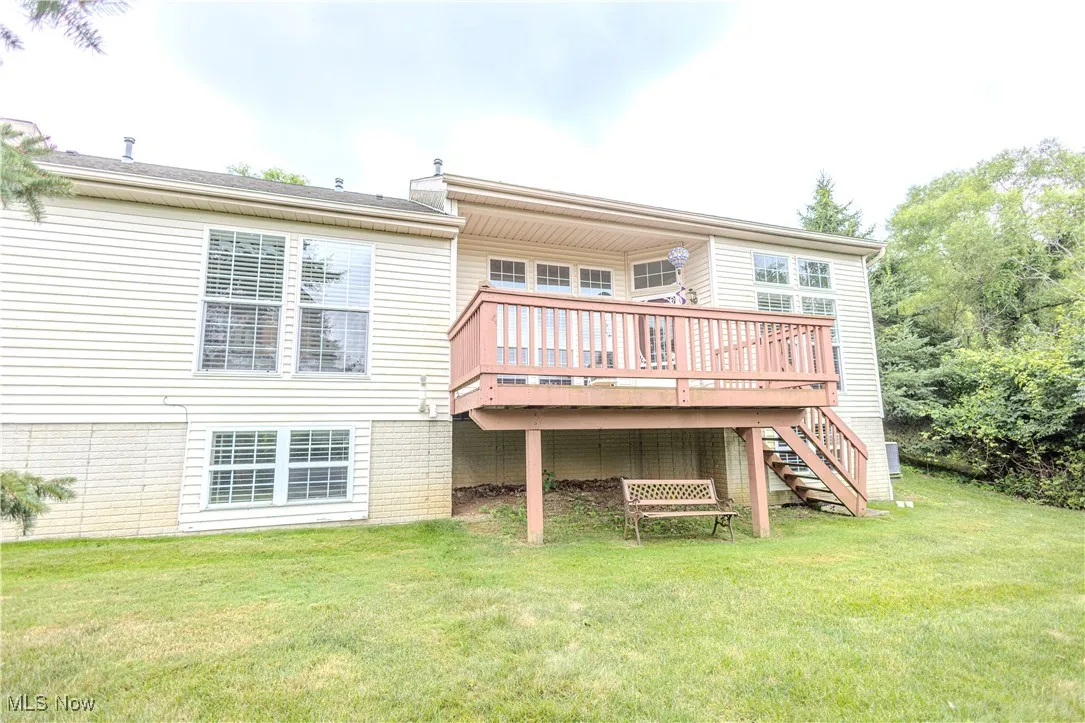 Back of house featuring a deck, a lawn, and stairway