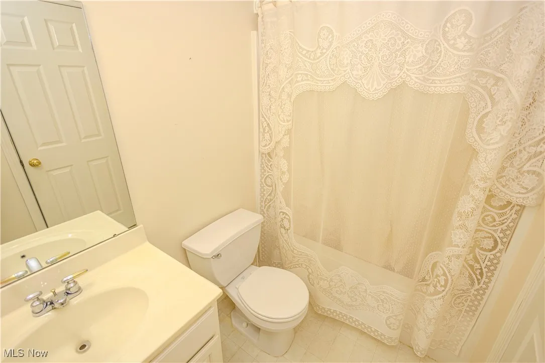 Bathroom featuring vanity, shower / bath combo with shower curtain, and tile patterned flooring