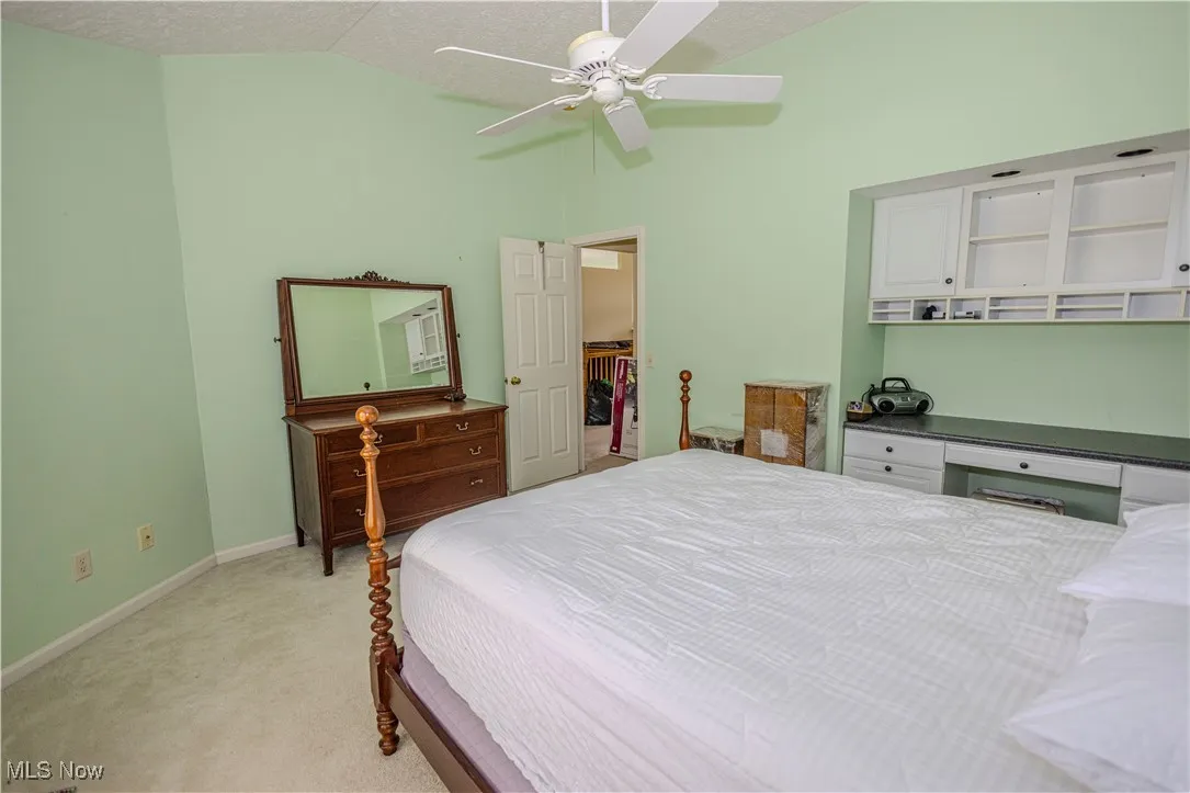 Bedroom with light colored carpet, a ceiling fan, and high vaulted ceiling