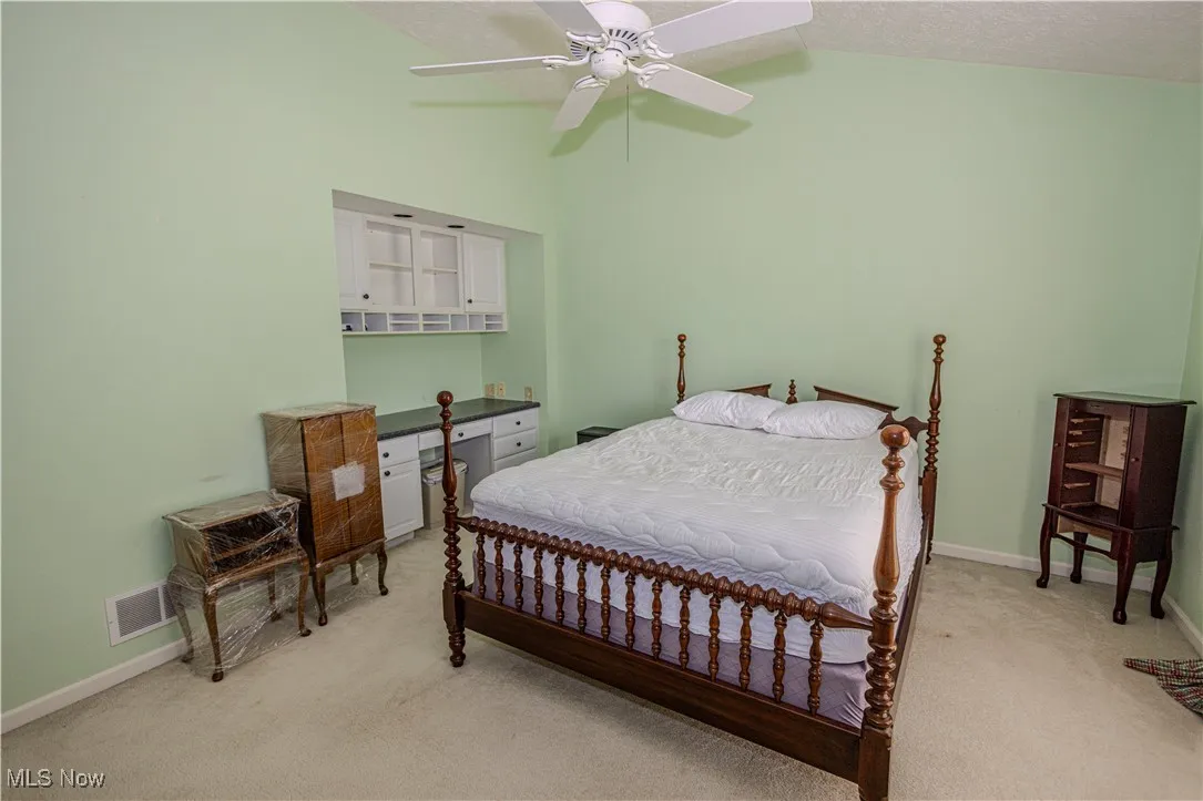Bedroom with light colored carpet, lofted ceiling, and a ceiling fan