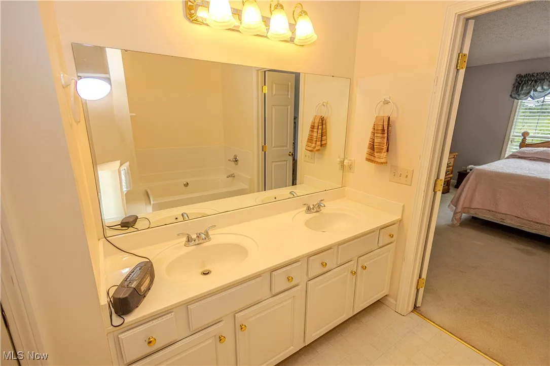 Bathroom with ensuite bath, a bath, and double vanity