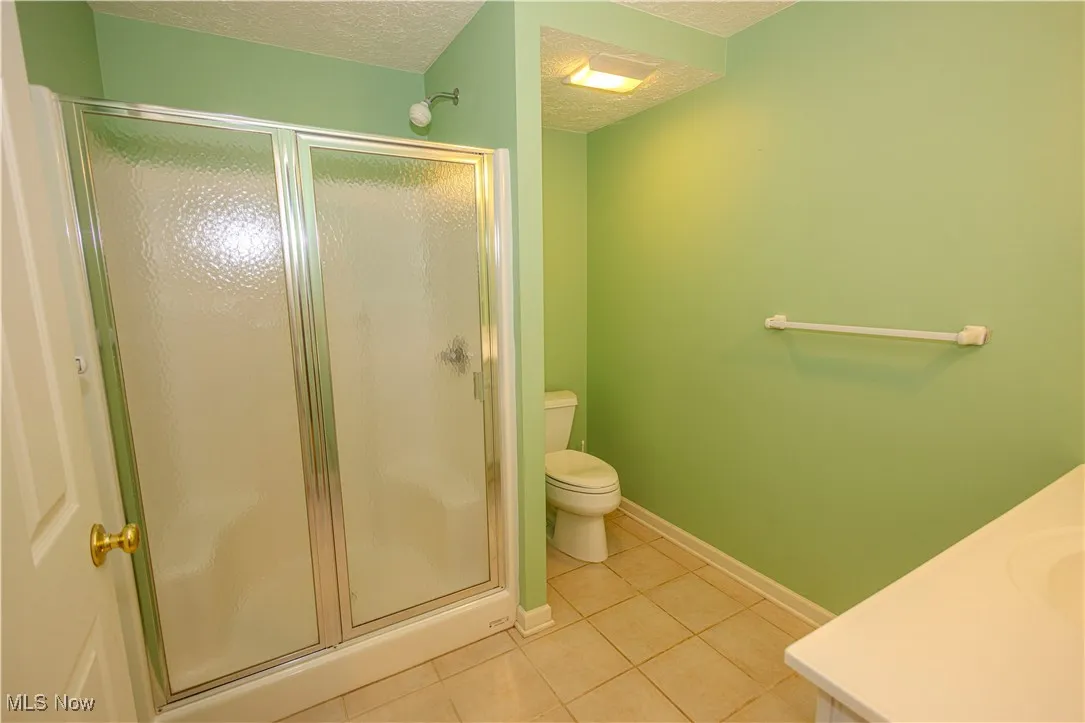 Bathroom with tile patterned flooring, a stall shower, a textured ceiling, and vanity