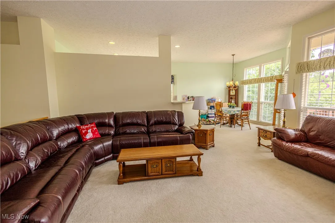 Carpeted living room featuring a textured ceiling, a chandelier, and recessed lighting
