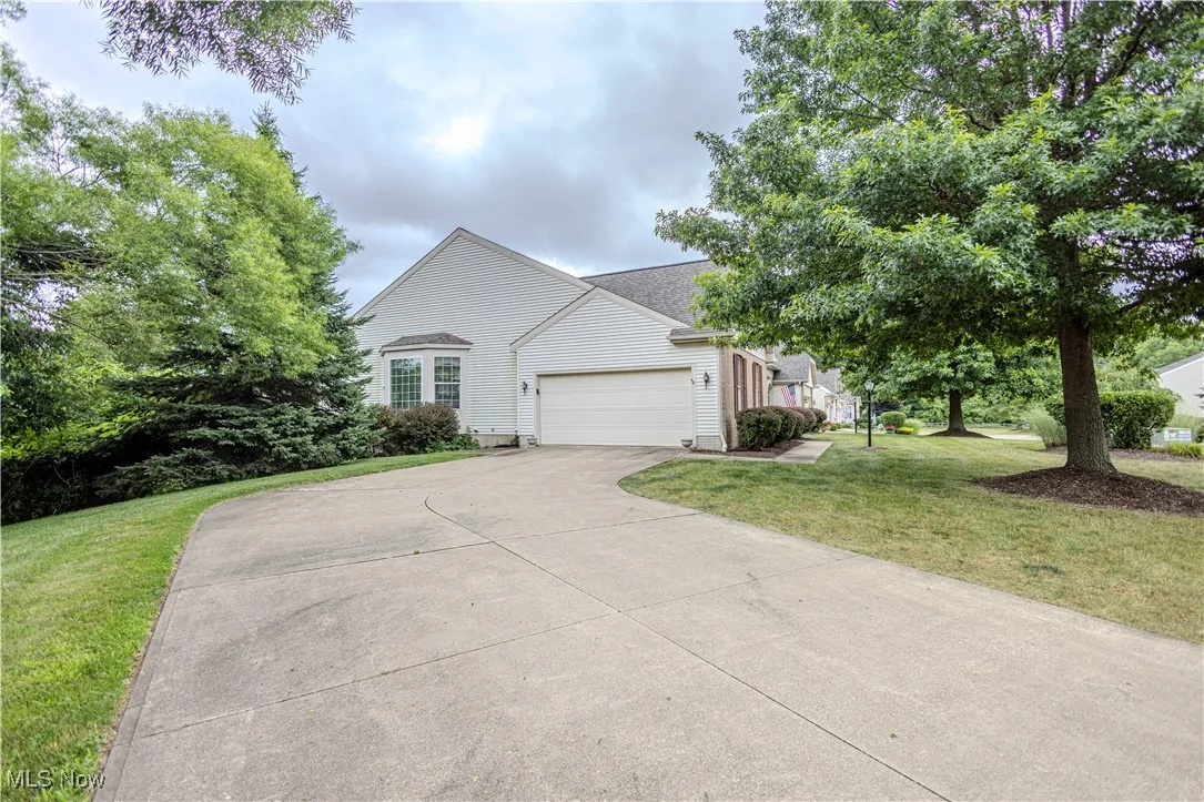 View of property hidden behind natural elements featuring a garage, driveway, and a front yard
