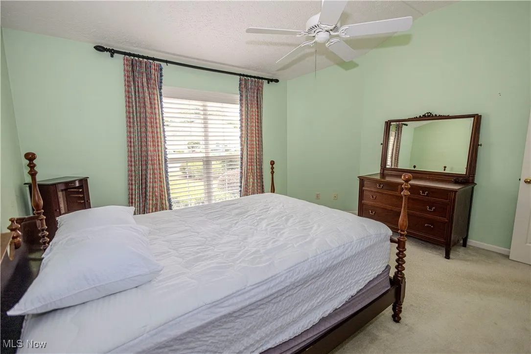 Bedroom featuring light colored carpet, a ceiling fan, and a textured ceiling