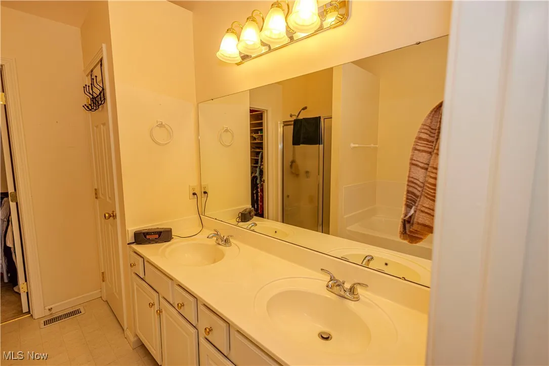 Full bath with a stall shower, double vanity, and a bath