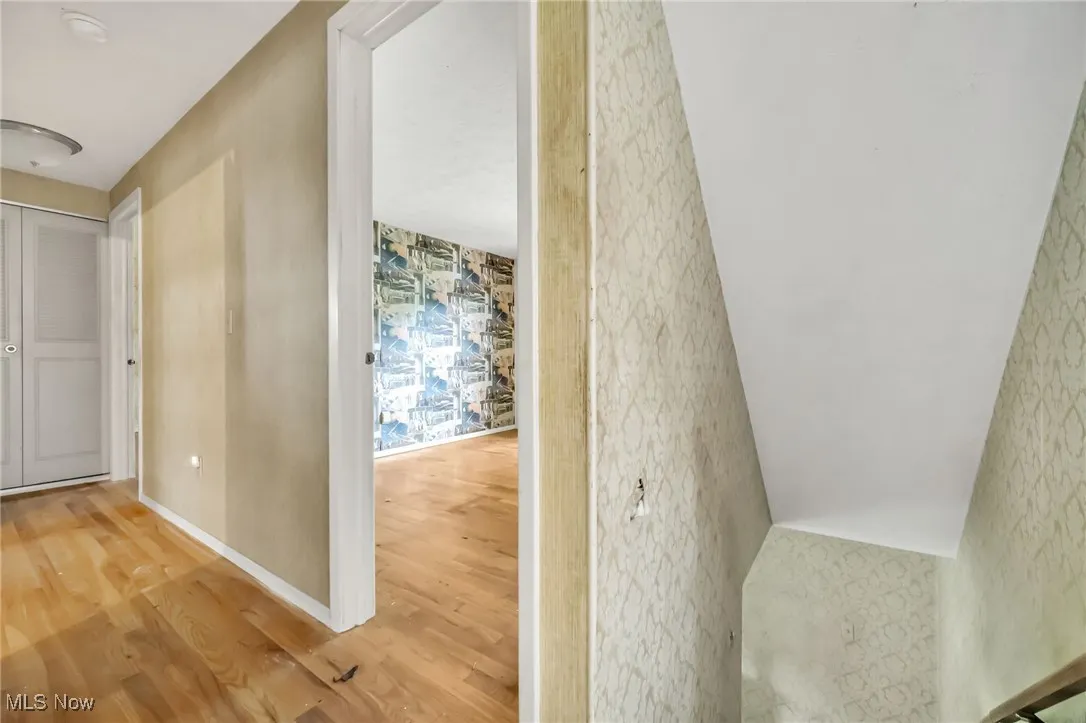 Hall featuring wallpapered walls and wood finished floors