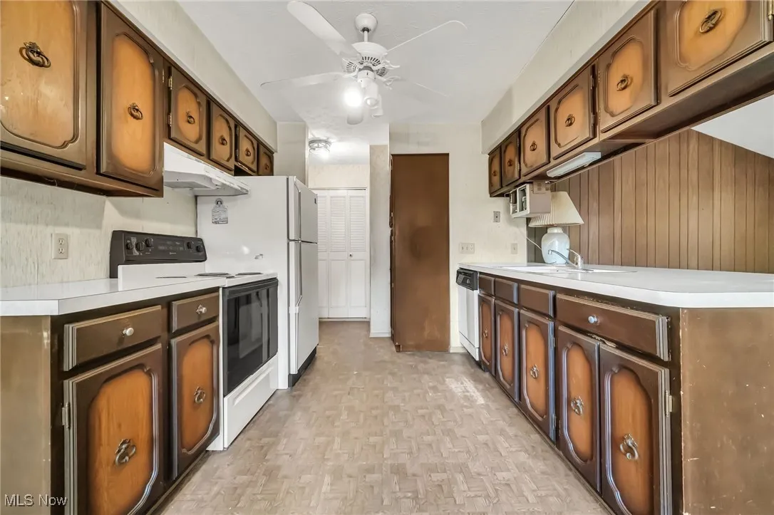 Kitchen featuring white electric range, ceiling fan, light countertops, under cabinet range hood, and dishwasher