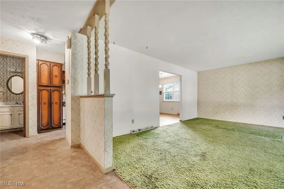 Empty room with wallpapered walls and light colored carpet