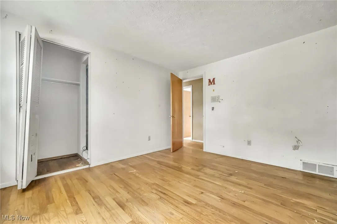 Unfurnished bedroom with light wood finished floors, a textured ceiling, and a closet