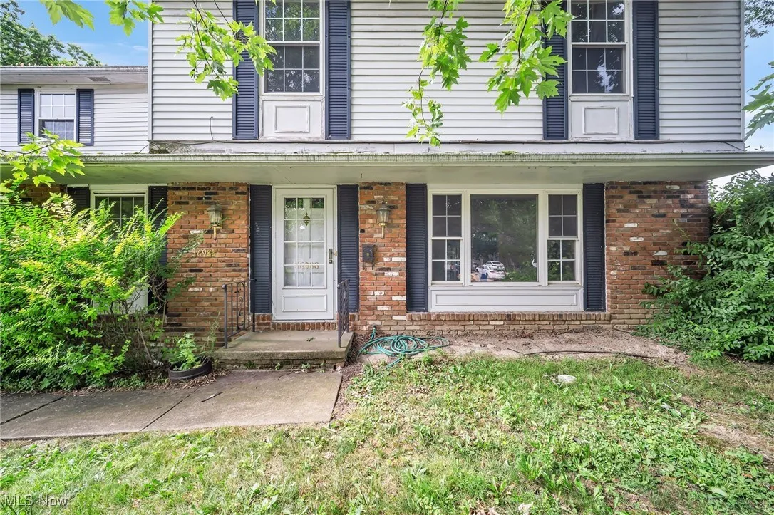 Doorway to property with covered porch and brick siding
