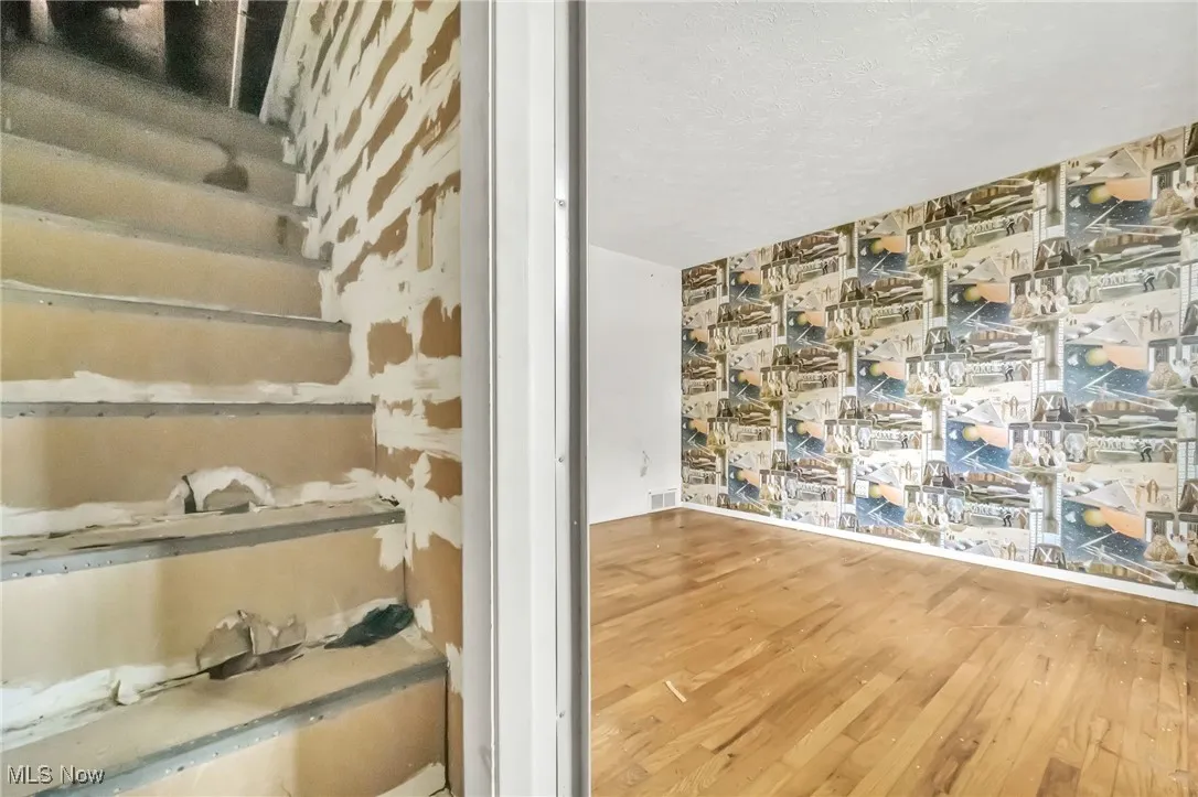 Stairway with wood finished floors and a textured ceiling
