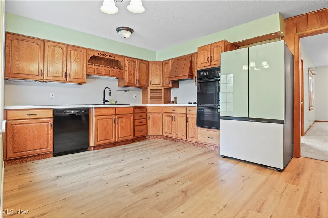 Kitchen featuring black appliances, light wood-type flooring, and light countertops