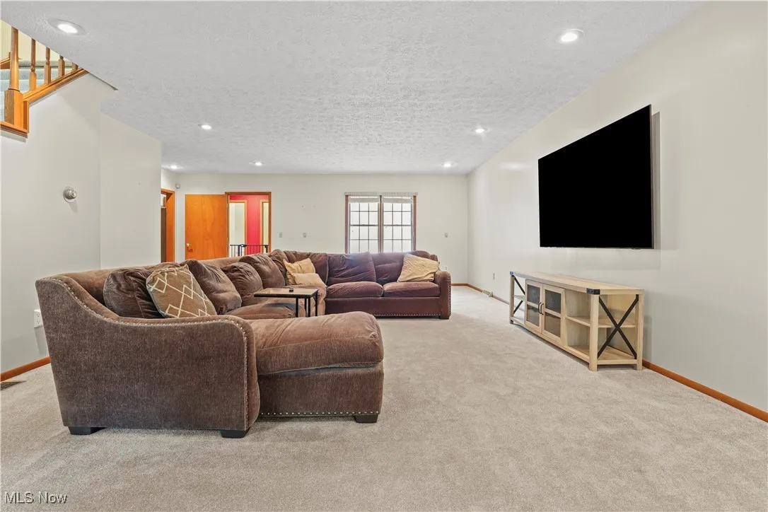 Living room with carpet flooring, recessed lighting, and a textured ceiling