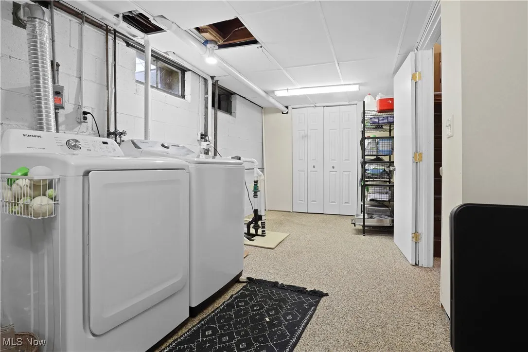 Laundry room featuring washer and dryer and concrete block wall
