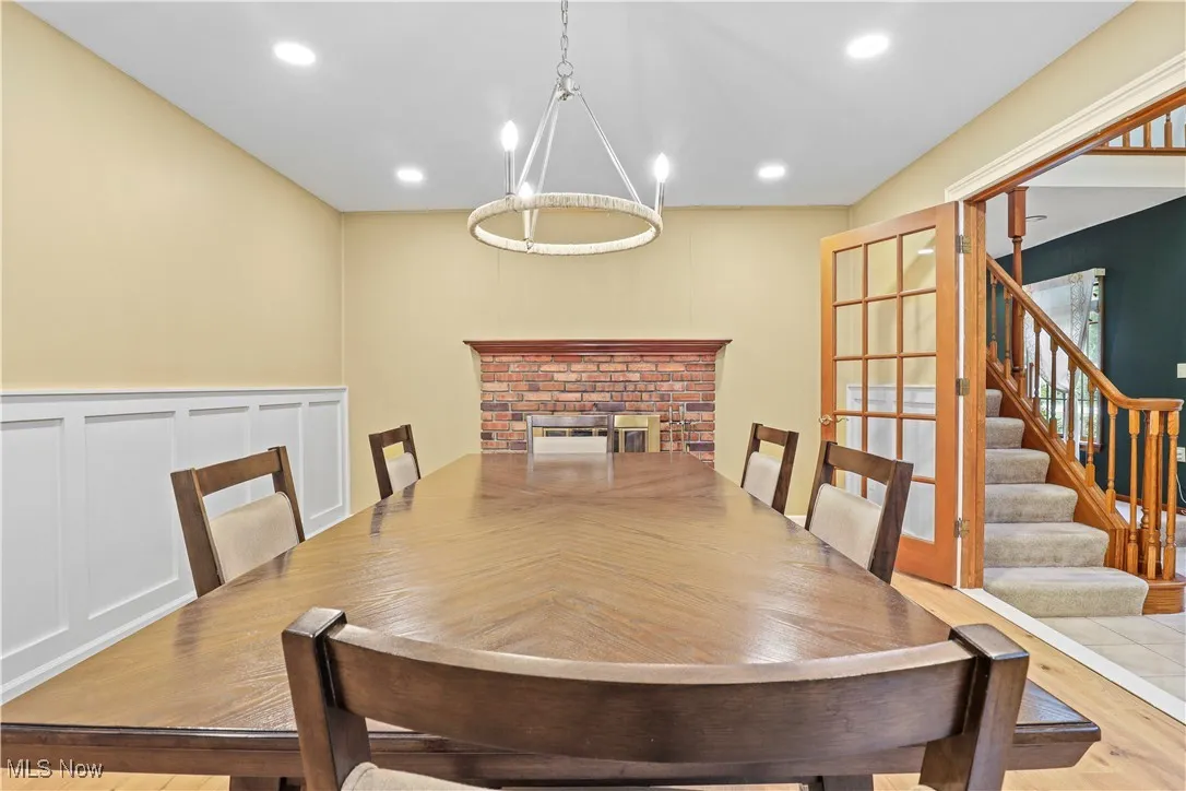 Dining space with a decorative wall, wood finished floors, stairway, a wainscoted wall, and recessed lighting