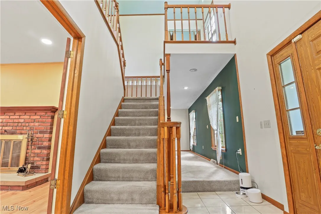 Staircase off the foyer featuring tile patterned floors, recessed lighting, and carpet