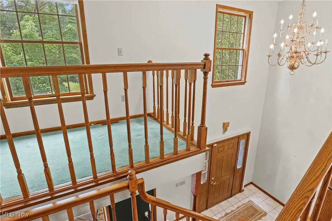 Staircase with a chandelier and tile patterned floors