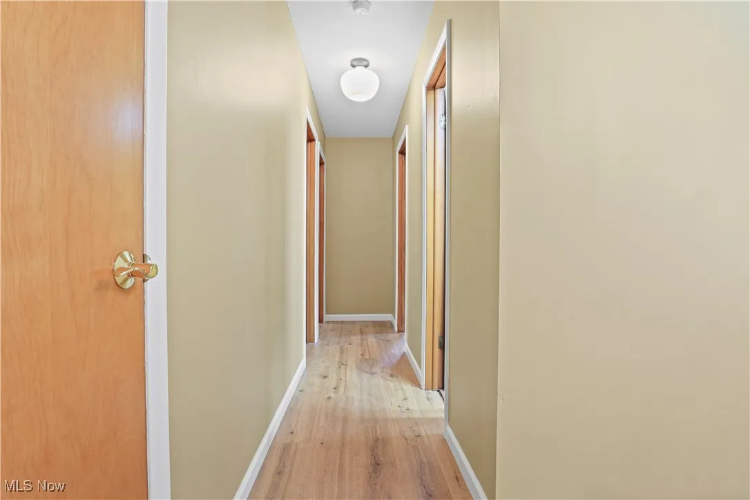 Hall featuring light wood-style flooring and baseboards