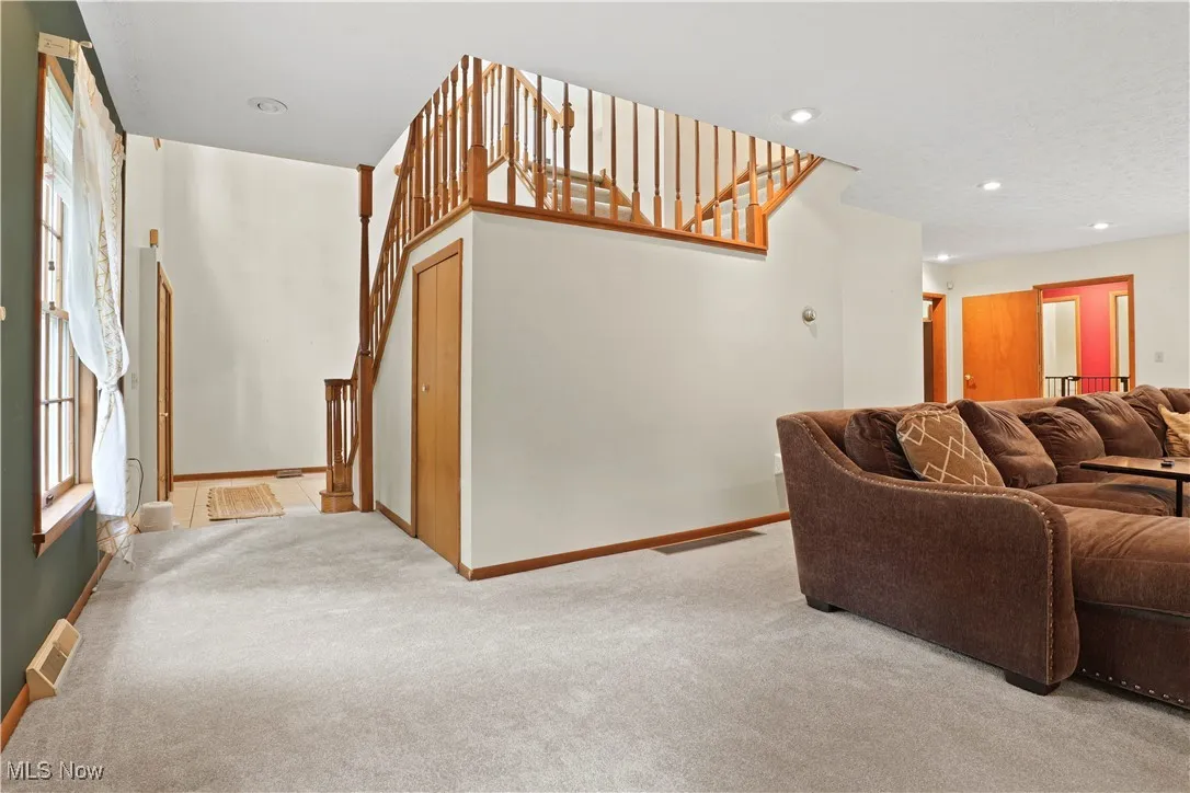 Living room featuring light colored carpet, plenty of natural light, stairs, and recessed lighting